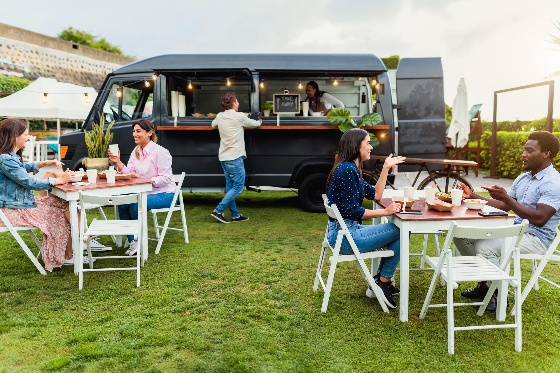 Happy multiracial people having fun eating in a food truck